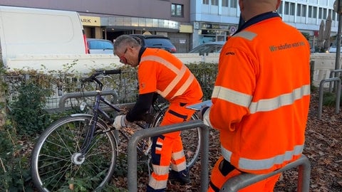 Zwei Mitarbeiter der Abfallwirtschaft und Stadtreinigung Freiburg schweißen ein Fahrradschloss auf, um den Fahrräder-Stellplatz am Hauptbahnhof zu räumen.