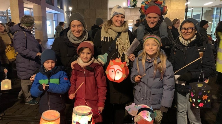 Eine Familie bei einem Laternenumzug mit selbstgebastelten Laternen.