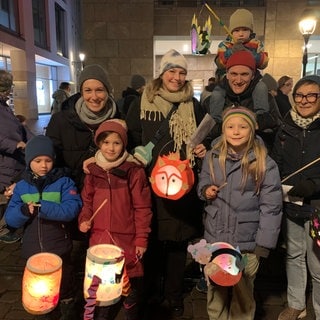 Eine Familie bei einem Laternenumzug mit selbstgebastelten Laternen.