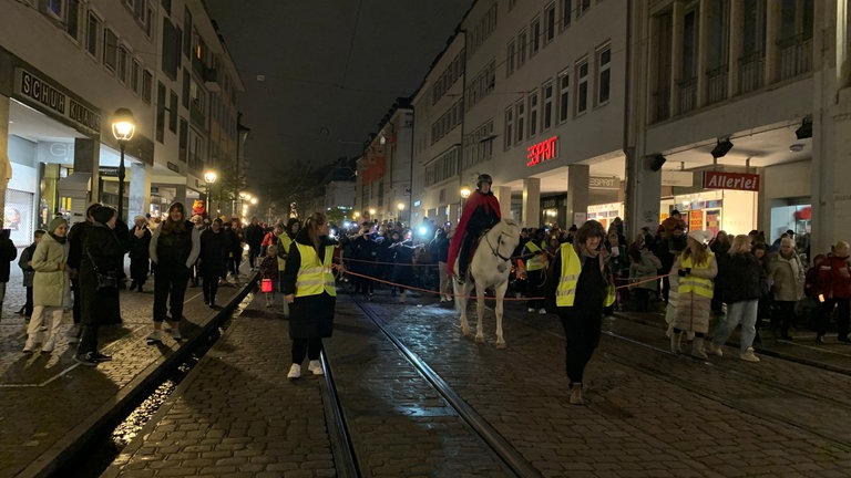 Laternenumzug, angeführt von Ross und Reiter durch die Innenstadt und Fußgängerzone von Freiburg.