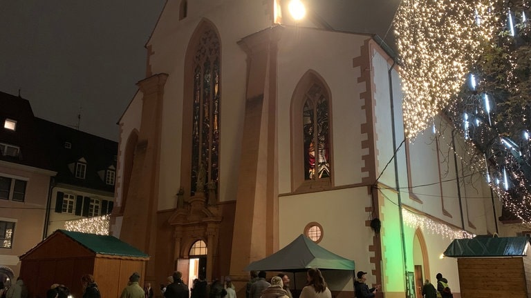 Die Martinskirche in der Freiburger Innenstadt von außen, im Dunkeln angestrahlt.