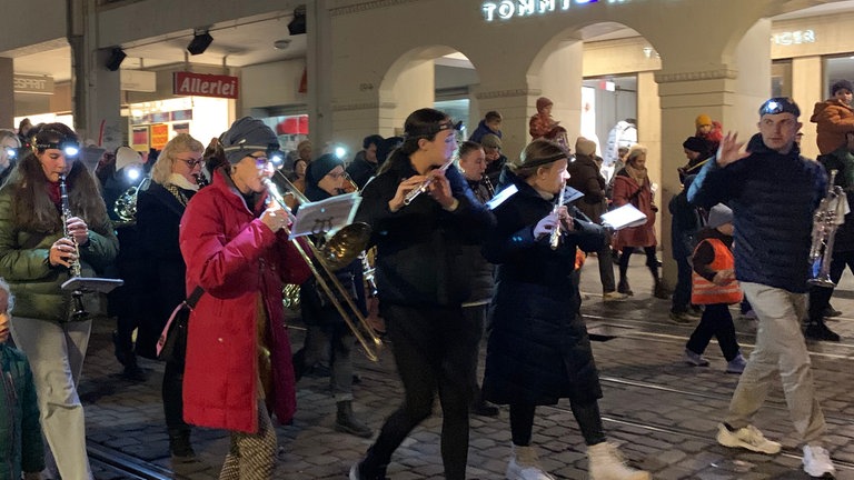 Eine Musikkapelle spielt bei einem Laternenumzug, mit Stirnlampeln, es ist dunkel.