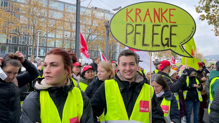 Ein junger Streikender der "ver.di Jugend" ist mit einem Schild zu sehen. Es trägt die Aufschrift "kranke Pflege".