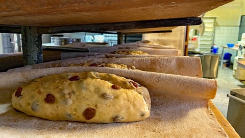 An Weihnachten werden viele Christstollen gebacken. Man sieht einen auf einem Backpapier.