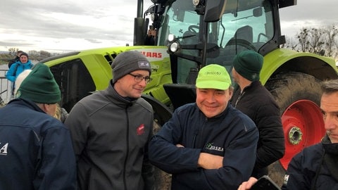 Männer stehen vor einem Traktor und warten das es los geht.