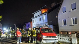 Menschen vor einem Haus, im oberen Dachgeschoss ist Feuer zu sehen - bei einem Brand in Willstätt ist ein Mensch schwer verletzt worden. Er musste über eine Drehleiter gerettet werden. 