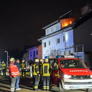 Menschen vor einem Haus, im oberen Dachgeschoss ist Feuer zu sehen - bei einem Brand in Willstätt ist ein Mensch schwer verletzt worden. Er musste über eine Drehleiter gerettet werden. 