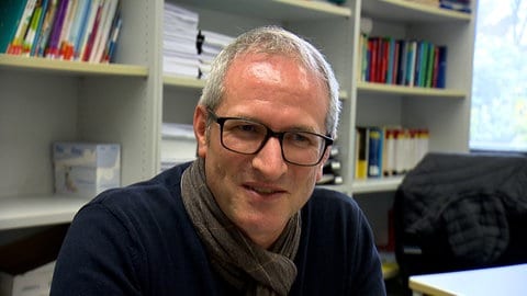 Sprach-Professor Andreas Krafft sitzt in seinem Büro vor seinem Bücherregal 