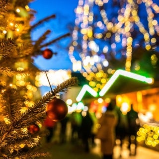 Eine Christbaumkugel hängt an einem Baum auf dem Freiburger Weihnachtsmarkt.