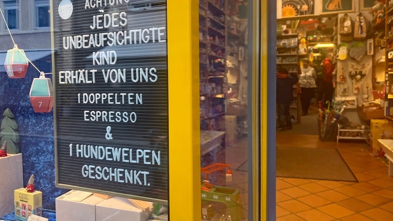 "Jedes unbeaufsichtigte Kind erhält von uns einen doppelten Espresso und einen Hundewelpen geschenkt", steht auf einem Schild in einem Freiburger Spielzeugladen