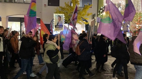 Etwa 500 Menschen haben am Montagabend in Freiburg gegen Gewalt an Frauen protestiert. Im Dunklen laufen die Demonstrierenden mit lila Fahnen und mit Plakaten. 