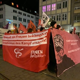 Zum Tag gegen Gewalt an Frauen hat in Freiburg eine Domenstration stattgefunden. Es ist dunkel. Die Teilnehmenden laufen mit Bannern, auf denen steht: "Gewalt an Frauen bekämpfen, Faschismus den Kampf ansagen!"