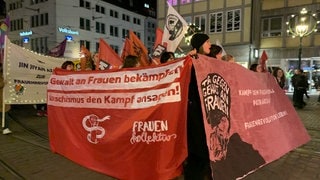 Zum Tag gegen Gewalt an Frauen hat in Freiburg eine Domenstration stattgefunden. Es ist dunkel. Die Teilnehmenden laufen mit Bannern, auf denen steht: "Gewalt an Frauen bekämpfen, Faschismus den Kampf ansagen!"