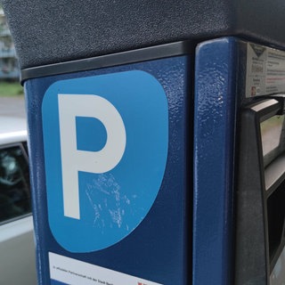 Parkautomat, im Hintergrund parkende Autos