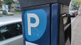 Parkautomat, im Hintergrund parkende Autos