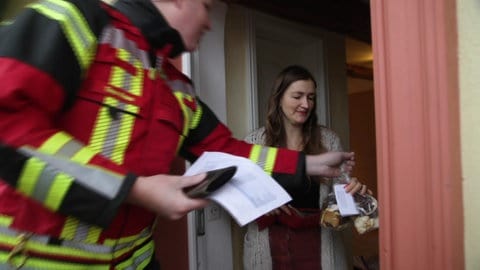 Eine Frau kauft Plätzchen an der Tür - die Feuerwehr Norsingen liefert selbstgebackene Plätzchen aus 