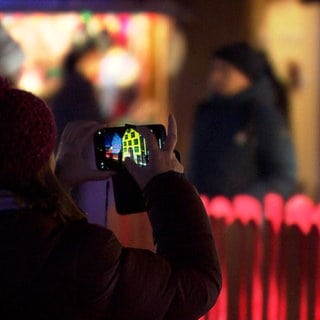 Eine Frau fotografiert ein Haus  - auch im kleinen Turckheim herrscht Weihnachtsstimmung beim Weihnachtsmarkt 