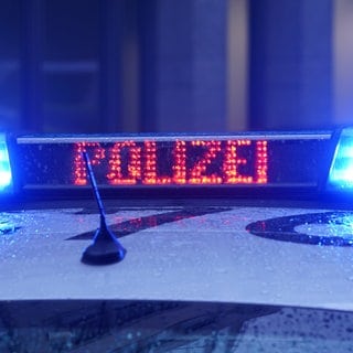 Der Schriftzug "Polizei" ist neben dem Blaulicht auf dem Dach eines Polizeiautos zu lesen.