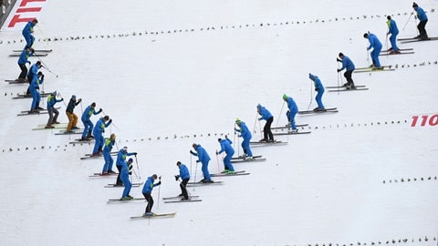 Mit Skiern präparieren Helfer beim Skisprung-Welt-Cup in Titisee-Neustadt die Hochfirstschanze.