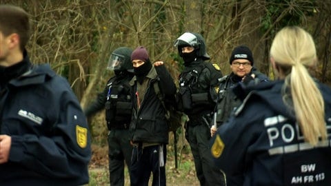 Polizisten führen einen Aktivisten aus dem besetzten Wald