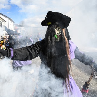 Ein Rhinwaldgeist aus Kehl hält beim Umzug der Bauernfastnacht einen Rauchtopf in der Hand