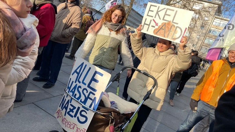 Mit Kinderwagen und klaren Botschaften: diese zwei Demostrierenden am Rande der Kundgebung auf dem Platz der Alten Synagoge.