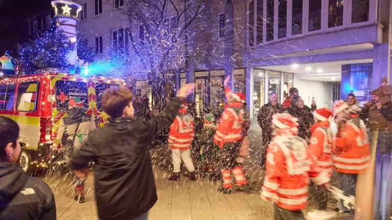 Weihnachtscorso der Rettungskräfte- ein Schaummaschine verbreitet Flocken, die fast wie Schnee aussehen