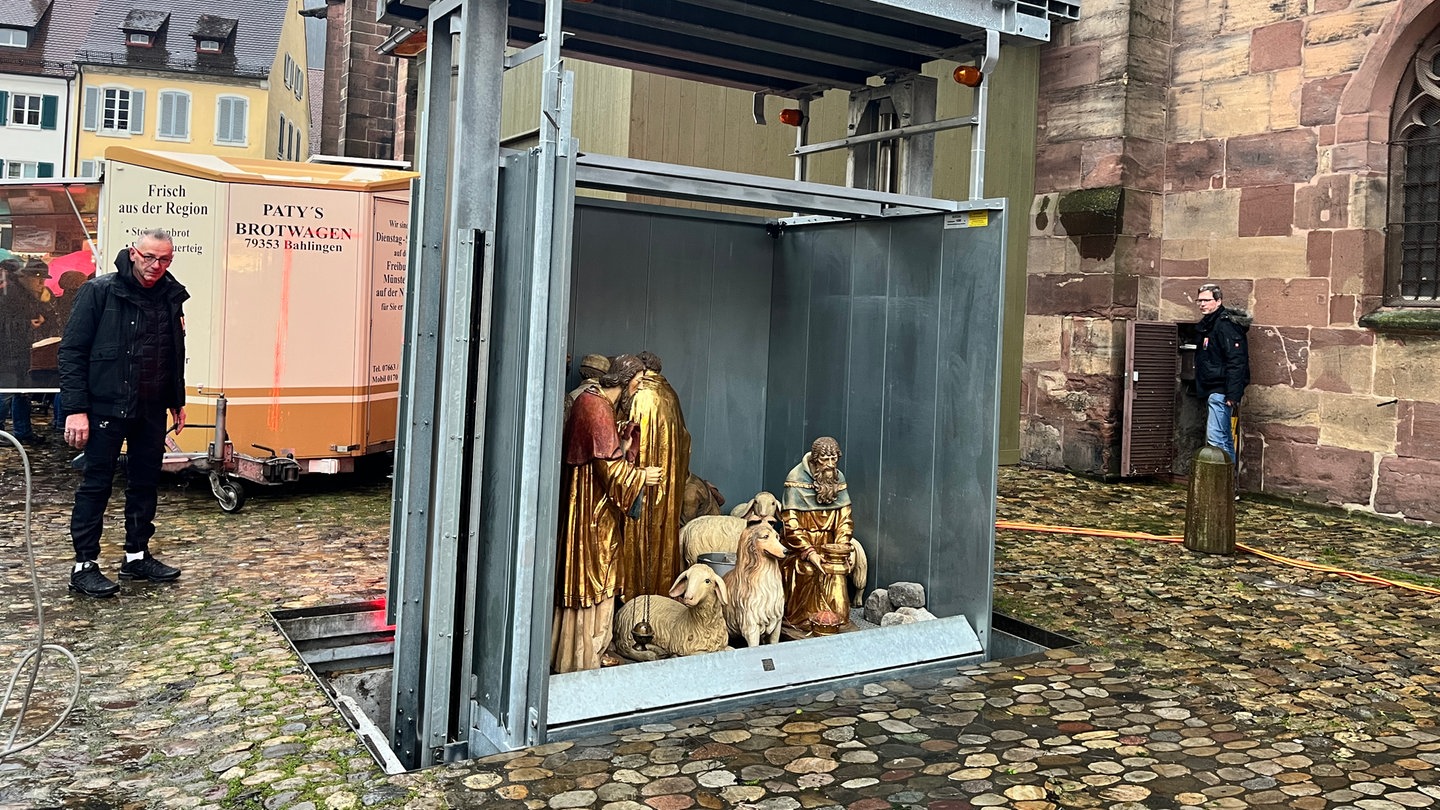 Ein skurriler Aufzug hebt die Krippe-Figuren auf den Münsterplatz in Freiburg.