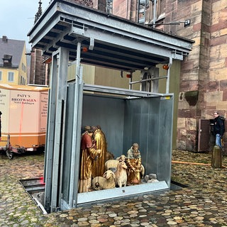 Ein skurriler Aufzug hebt die Krippe-Figuren auf den Münsterplatz in Freiburg.