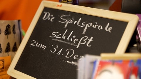 Neben der Kasse stetht auf einer Tafel die Aufschrift: "Die Spielspirale schließt zum 31. Dezember"