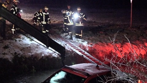 Feuerwehrleute bergen einen Pickup, der bei Glatteis in die Schutter gestürzt ist. 