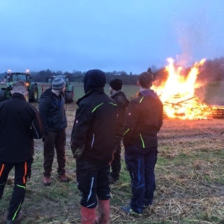 Eine Gruppe von Landwirten steht in Lahr im Ortenaukreis vor einem Mahnfeuer, das zum Jahrestag der Bauernproteste am 8. Januar angezündet wurde.