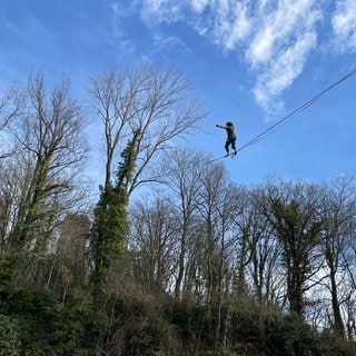 Ein Mann auf einer 20 Meter hohen Slackline am Freiburger Schlossberg