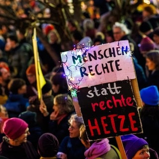 Während einer Demonstration gegen die Migrationspolitik der Union auf dem Platz der Alten Synagoge in Freiburg ist ein Schild mit der Aufschrift "Menschrechte statt rechte Hetze" zu sehen.