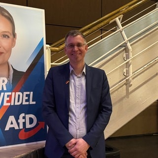 Der AfD-Kandidat des Wahlkreises Emmendingen-Lahr neben einem Wahlplakat der Kanzler-Kandidatin Alice Weidel.