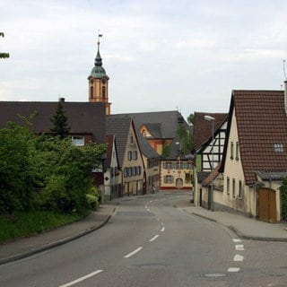 Hauptstraße von Merdingen. Im Hintergrund ist der rot-gelbe Kirchturm zu sehen.