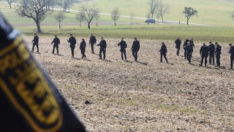 Polizeibeamte in Steinen suchen die Gegend rund um den Fundort des toten Säuglings ab.