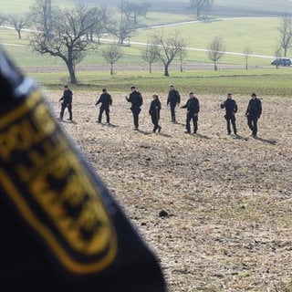 Polizeibeamte in Steinen suchen die Gegend rund um den Fundort des toten Säuglings ab.