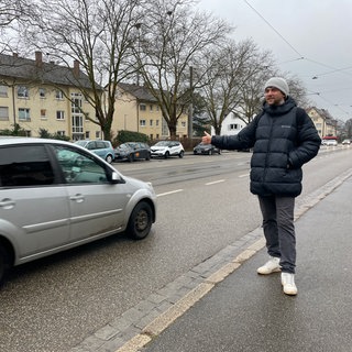 Ein junger Tramper hofft auf eine Mitfahrgelegenheit in Freiburg-Littenweiler