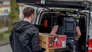 Bei einer Wohnungsdurchsuchung durch die Polizei werden beschlagnahmte Gegenstände in eine Auto geladen.