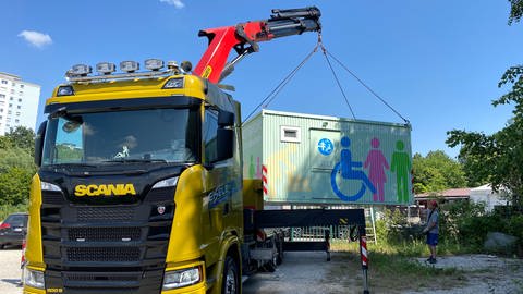 Ein Kranwagen lädt in Reutlomgen die "Toilette für Alle" auf