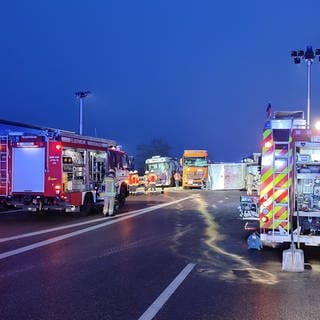 Mehrere Feuerwehrfahrzeuge, im Hinterdrund die verunfallten Lastwagen