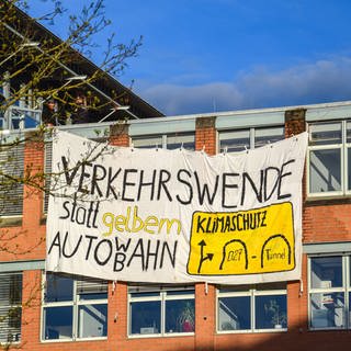 Protestplakat am Regierungspräsidium in Tübingen mit der Aufschrift: Verkehrswende statt gelbem Auto WB ahn. Mitglieder der Klimaaktivistinnen Tübingen klettern am 04.04.2024 auf das dach des Regierungspräsidiums und besfestigen ein Plakat als Protest gegen den Neubau eines B27 Tunnels 