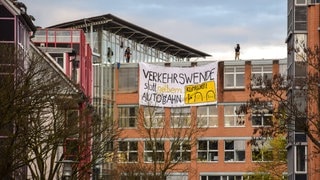 Protestplakat am Regierungspräsidium in Tübingen mit der Aufschrift: Verkehrswende statt gelbem Auto WB ahn. Mitglieder der Klimaaktivistinnen Tübingen klettern am 04.04.2024 auf das dach des Regierungspräsidiums und besfestigen ein Plakat als Protest gegen den Neubau eines B27 Tunnels 