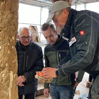 Drei Männer schauen sich den Geldfund an