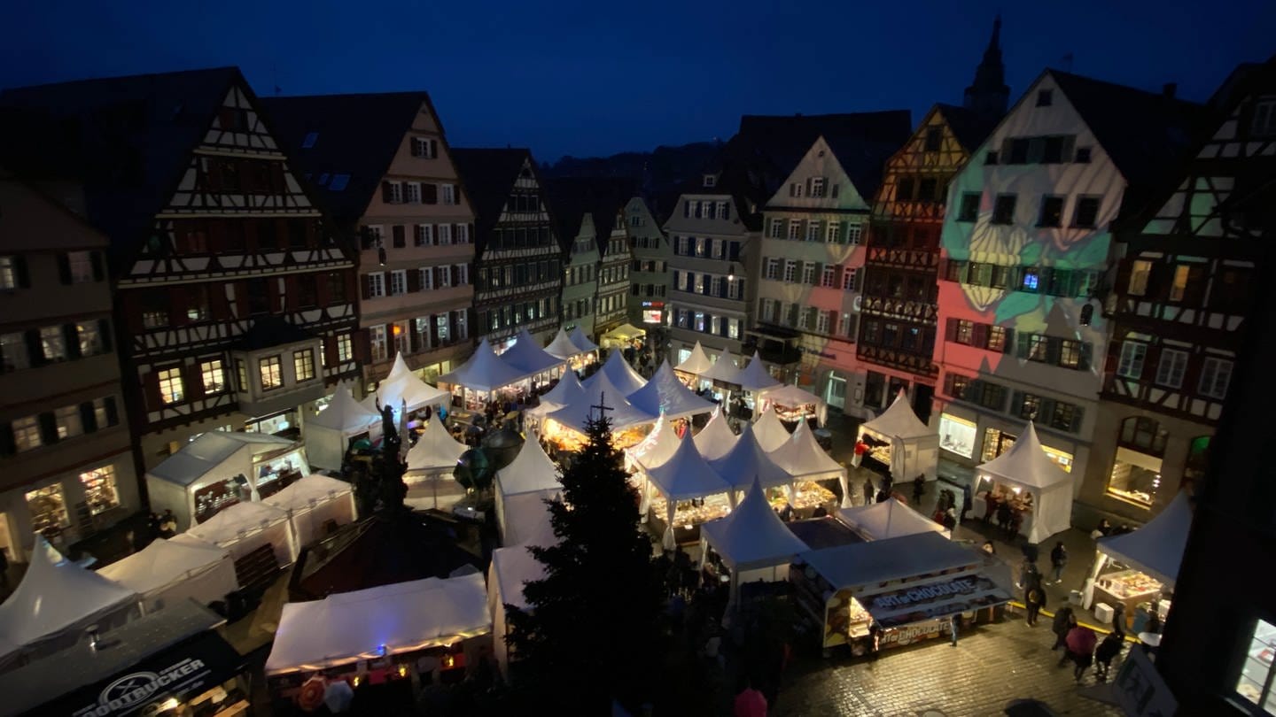 Blick auf den Marktplatz in Tübingen am Abend mit stimmungsvoll beleuchteten Ständen des Schokoladenfestivals 