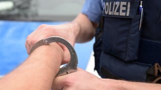 Polizist legt Handschelle an (Symbolbild)