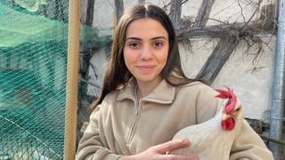 Leonore Ymeri aus Rottenburg hält ein Huhn auf dem Arm