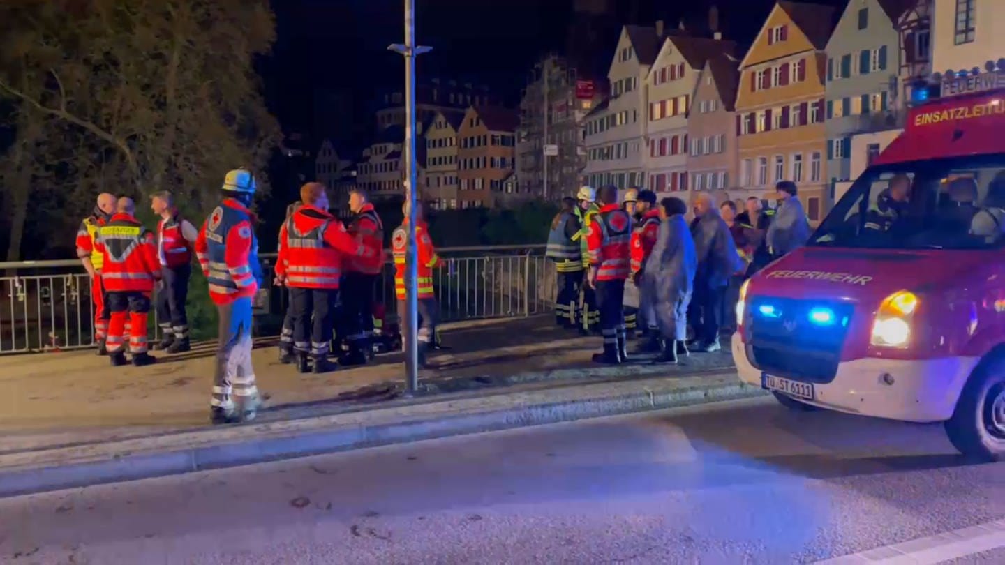 Auf der Eberhardsbrücke in Tübingen stehen Rettungskräfte, um den Insassen eines gekenterten Stocherkahns auf dem Neckar zu helfen
