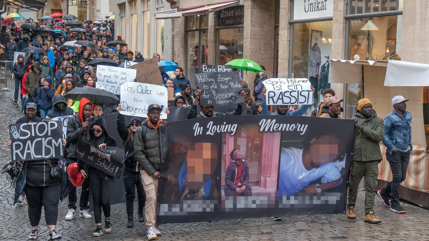 Mesnchen demonstrieren in Tübingen gegen die Äußerungen von OB Palmer zum gewaltsamen Tod eines jungen Gambiers. Dabei tragen sie ein Transparent mit Bilder des Ermordeten.